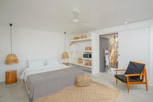 een witte slaapkamer met een bed en een stoel bij Tamu Koh Rong in Koh Rong Island
