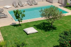 una piscina en un patio con sillas y árboles en Mangie Villa, en Hersonissos