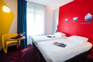 a hotel room with two beds and a red wall at Ibis Styles Rouen Centre Cathédrale in Rouen