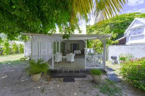 a white gazebo in the yard of a house at La Case Creole in Roches Noires