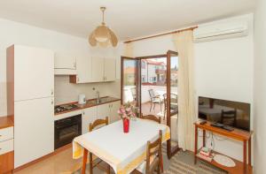 a kitchen and dining room with a white table with a vase of flowers at Apartments Joso in Zadar