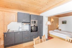 a kitchen with gray cabinets and a bed in a room at Ehrenbachhöhe on Top of the Mountain in Kitzbühel