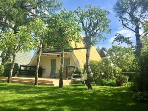 a yellow house with trees in the yard at Domek Letniskowy Głebinów in Nysa