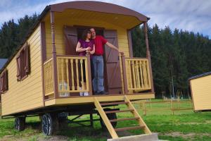 Ein Mann und eine Frau stehen auf der Veranda eines winzigen Hauses in der Unterkunft L' Instant Ch' Oizy in Oizy