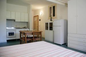 una cucina con tavolo e frigorifero bianco di Appartamenti Maricampo by HelloElba a Marina di Campo