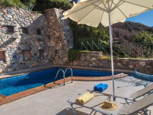 a pool with an umbrella and a table and chairs at Meliti Sunset View & Private Pool Villa 20 min from Elafonissi in Livadia +18 photos