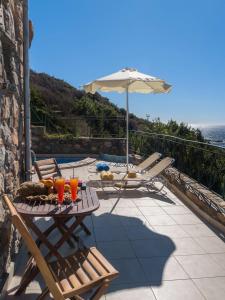 a patio with a table and chairs and an umbrella at Meliti Sunset View & Private Pool Villa 20 min from Elafonissi in Livadia