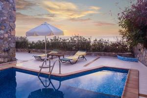 a pool with an umbrella and two chairs and a table and a table at Meliti Sunset View & Private Pool Villa 20 min from Elafonissi in Livadia