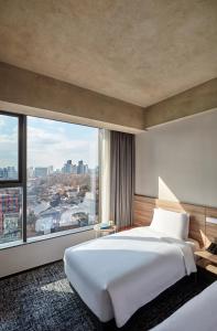 una camera da letto con un grande letto bianco e una grande finestra di HOTEL in 9 Gangnam a Seul