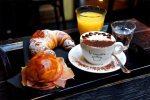 a tray with a cup of coffee and a croissant and a drink at B&B Vecchia Suppenna in Andria