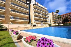 a large apartment building with a swimming pool and flowers at Residencial Ventura Park / Royal / Jerez in Salou