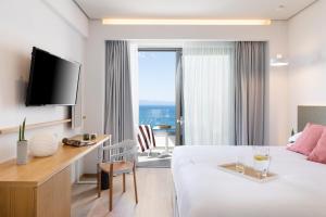 a hotel room with a bed and a desk and a tv at Messinian Icon Hotel & Suites in Kalamata