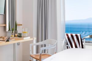 a bedroom with a desk and two chairs and a window at Messinian Icon Hotel & Suites in Kalamata