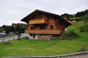 a wooden house on a hill with a green field at Ferienwohnungen Hotel Alpina in Adelboden