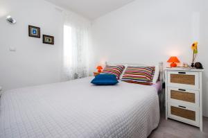 biała sypialnia z białym łóżkiem z niebieskimi poduszkami w obiekcie Apartman Delfin w Rovinj
