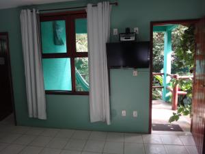 sala de estar con TV y ventana en Pousada Maresia, en Itacaré