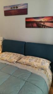 un letto con testiera blu e un dipinto sul muro di La casa di Perpy Ivrea centro storico a Ivrea