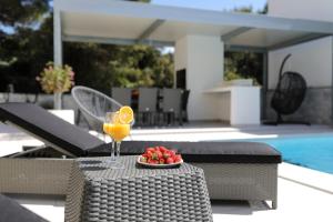 a glass of orange juice and a plate of fruit on a table at Luxury Villa Nada with Pool in Petrcane