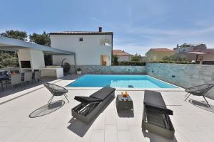 a swimming pool with two chairs and a table at Luxury Villa Nada with Pool in Petrcane
