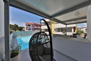 a wicker chair sitting on a balcony next to a swimming pool at Luxury Villa Nada with Pool in Petrcane