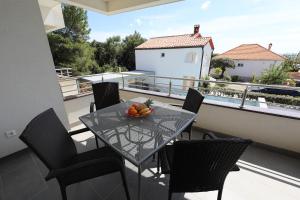 a table with chairs and a bowl of fruit on a balcony at Luxury Villa Nada with Pool in Petrcane