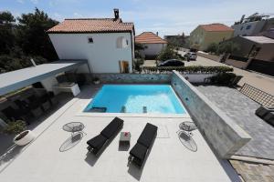 a swimming pool on a patio with lounge chairs and a swimming poolvisor at Luxury Villa Nada with Pool in Petrcane
