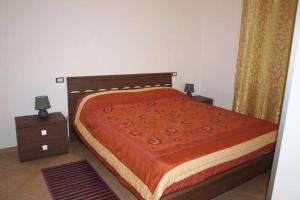 a bed with an orange blanket and two night stands at Appartamento tra mare e montagna in Baunei