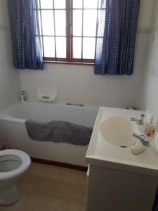 a bathroom with a tub and a toilet and a sink at Eindelik in Simonʼs Town