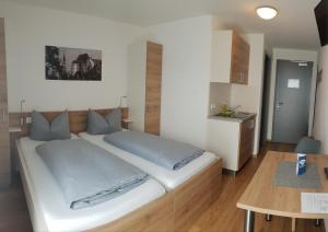 ランツフートにあるeasy sleep Apartmenthotelのテーブル付きの客室で、白い大型ベッド1台が備わります。