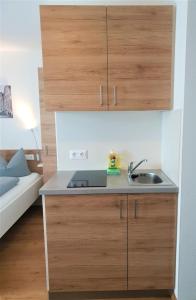 a kitchen with a sink and wooden cabinets at easy sleep Apartmenthotel in Landshut
