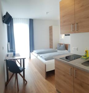 a bedroom with a bed and a desk and a kitchen at easy sleep Apartmenthotel in Landshut