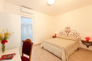ein Schlafzimmer mit einem Bett und einem Tisch mit einer Blumenvase in der Unterkunft Il Giardino dell'Osa in Fonteblanda