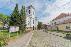 una iglesia blanca con una torre de reloj en una calle en Pension U kostela, en Český Brod