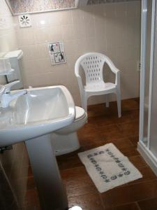 a bathroom with a sink and a toilet and a chair at Alojamento Local Céu-Azul in Porto de Mós