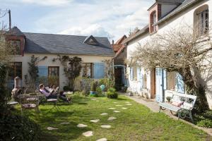 ミタンヴィルにあるMaison d'Hotes à l'Ombre Bleueの家の庭に座る二人