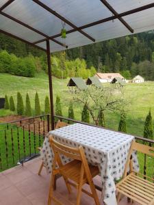 a table and chairs on a balcony with a view of a field at Balázs Holiday Apartment in Băile Tuşnad