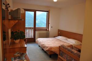 sypialnia z łóżkiem i dużym oknem w obiekcie Albergo Dolomiti w mieście Capriana