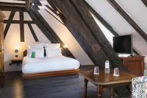 a bedroom with a bed, chair, desk and a tv at Hôtel de l'Europe by HappyCulture in Strasbourg