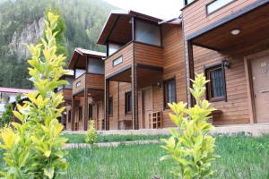 a row of wooden buildings with mountains in the background at Uzungol Selale otel Bungalow in Uzungöl