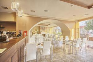 a restaurant with white chairs and tables and a counter at Inza Hotel in Druskininkai