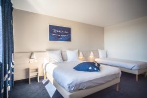a hotel room with two beds and a blue pillow at Ace Hôtel Le Mans in Saint-Saturnin