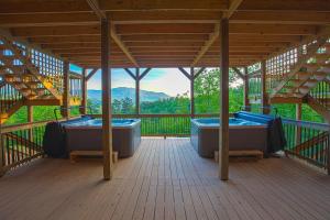 Una terraza de madera con dos jacuzzis en un edificio. en Gatlinburg Mansion Cabin, en Pittman Center