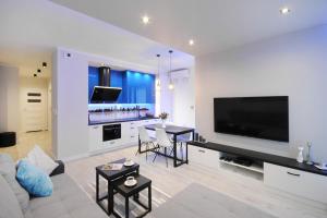 a living room with a large television and a kitchen at P&O Serviced Apartments Solec in Warsaw