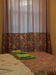 a bed with green pillows and a window with a curtain at Rīgas 20/1 apartaments in Cēsis