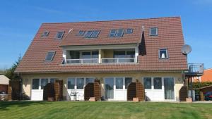 een huis met een rood dak en een tuin bij Haus Inselperle mit Blick auf den Bodden in Alt Reddevitz