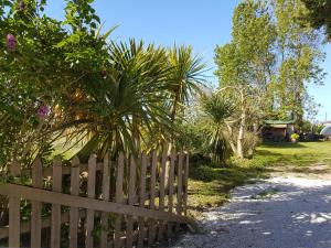 a wooden fence next to a yard with palm trees at La Casa Céline in Surtainville