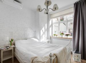 a white bedroom with a bed and a white brick wall at Too-Good Apartments in Kraków