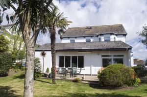 ein weißes Haus mit Palmen im Hof in der Unterkunft Gyllyngvase House in Falmouth
