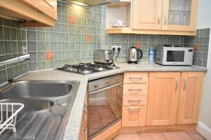 a kitchen with a sink and a stove and a microwave at East Claremont - beautiful 2BR apartment in Central Edinburgh in Edinburgh