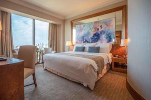 Gulf Hotel Bahrain في المنامة: غرفة نوم بسرير كبير عليها لوحة كبيرة